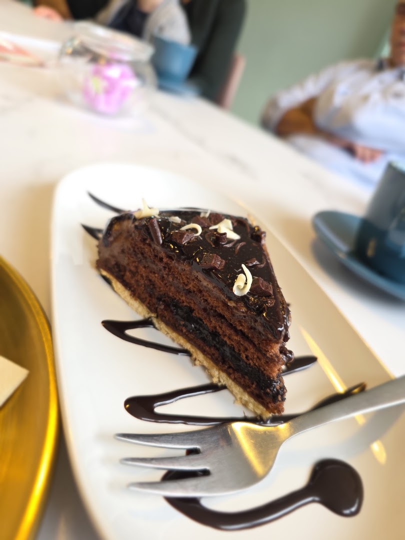 Kuchenstück mit Schokoladensauce und Kaffee